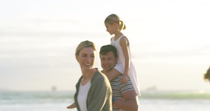 Happy, playful and carefree caucasian family walking on the beach while on vacation or holiday on a sunny day. Mom and dad having fun with their children enjoying the weekend at the sea or ocean