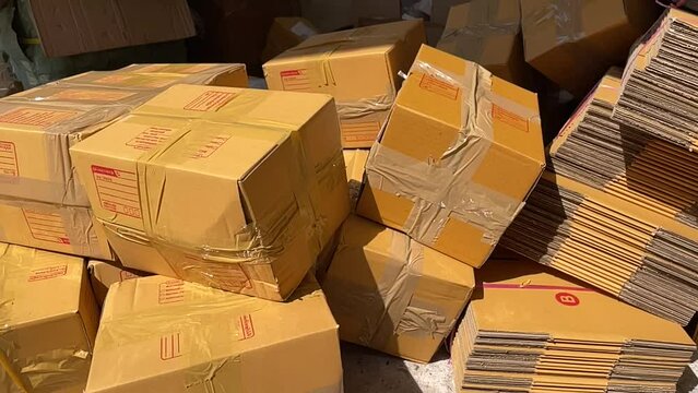 Tossing brown box package to pile of parcel boxes slow motion on a sunny day