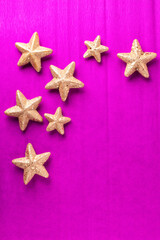 Layout with big and small golden decorative stars on bright pink paper textured background. Top view. Christmas, New Year holidays concept.  Place for text.