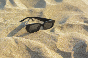 Fototapeta na wymiar Stylish sunglasses on sandy beach, space for text