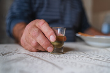 Fototapeta na wymiar A close up of grandfathers hand holding a glass of rakija alcoholic drink