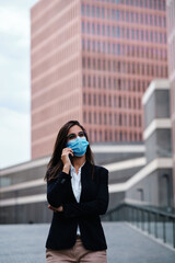 Businesswoman with protective mask using the mobile outdoors