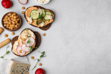 Delicious sandwiches with hummus and different ingredients on light grey background, flat lay. Space for text