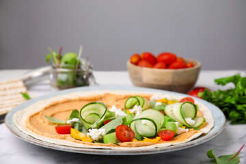 Tortilla with hummus and vegetables on table, closeup