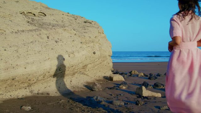 Female on a deserted beach in full growth.
A young woman looks around and prepares to undress on the beach. 
Relax on a deserted beach by the ocean.