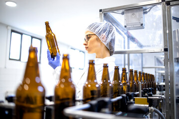Female factory supervisor controlling beer production in alcohol beverage bottling plant.