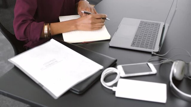 Creative professional taking notes and brainstorming ideas for a new design project of opportunity. Aerial closeup of a business woman writing in her notebook while working at her desk in the office