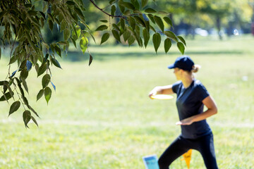 Woman playing flying disc golf sport game in the park