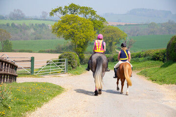 Two horse riders enjoying the views over the Shropshire countryside as they hack out together, one on a horse the other a pony .