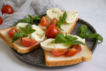 Bread with mozzarella cheese, tomato on a light background