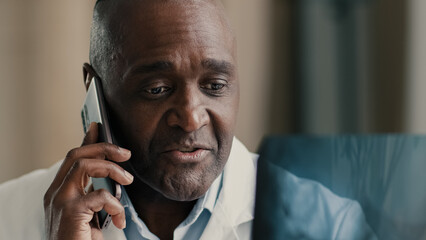 Medical diagnostics experienced mature senior african man surgeon radiologist look at x-ray image tomography check health results analyzing 3d photo doctor talk mobile phone consulting patient distant