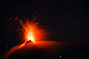 Fototapeta na wymiar Fuego eruption over clouds and stars