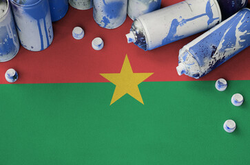 Burkina Faso flag and few used aerosol spray cans for graffiti painting. Street art culture...