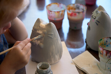The child is decorated with a clay piggy bank with paints