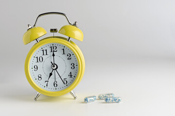 alarm clock on a light background with pills