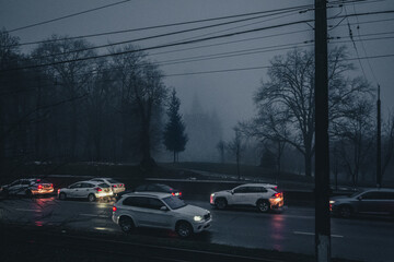 Fototapeta na wymiar Traffic in the evening in the fog against the background of a prayer house in the city of Vinnitsa, Ukraine