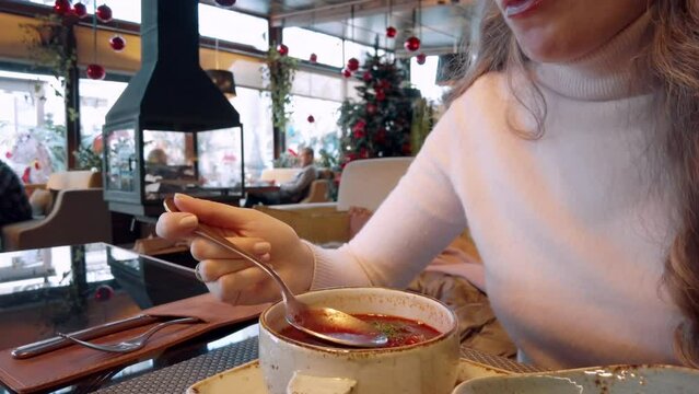 Woman eating red ukrainian borsch soup at a restaurant