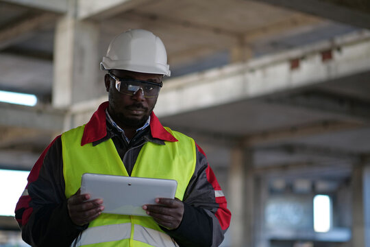 African american worker holds in hands tablet computer and looks at camera