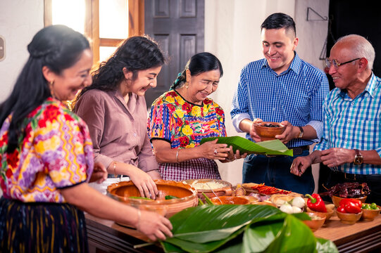 Una feliz familia latina se divierte cocinando una tradición guatemalteca con sus nietos.