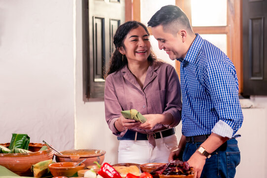 Pareja latina moderna de  marido y mujer  cocinan  juntos tamales para conservar sus tradiciones. 