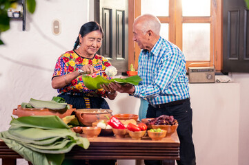 Pareja de ancianos preparando tamales, un platillo tradicional guatemalteco.