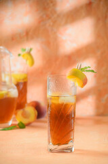 peach iced tea Jug in the background. Shadows on a melon-colored background.