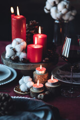 Rustic table decor for Christmas or New Year family dinner. Centrepiece with red candle, dry orange, cone, cinnamon, anise. Zero waste eco-friendly home. Cozy atmosphere, dark background. Close up
