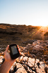 First person view of a hiker looking at a gps at sunset