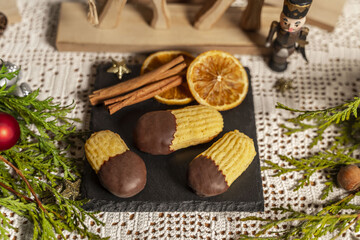 Orangenstäbchen, Plätzchen auf einer Schieferplatte mit weihnachtlicher Dekoration
