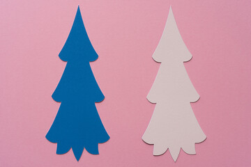 two stylized paper holiday trees on pink