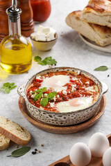 Traditional north african dish shakshouka made of eggs poached in a sauce of tomatoes, olive oil, bell peppers, onion and garlic, spiced with cumin, paprika and cayenne pepper