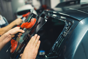 Windshield or rear window removal with the use of suction cups. Indoor closeup portrait. Two...