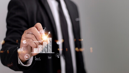 Businessman draws an increasing trend arrow and a rising chart from plan to goal. It is a representation of the idea of corporate investment development.