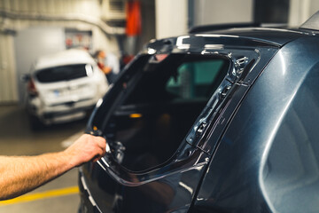 Inside mechanic's garage. Hand of a caucasian man removing glue residues before the installing...