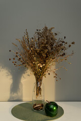 Bouquet of dried flowers on the table in a glass vase, in the light of the sun, contrasting image, with bright shadows