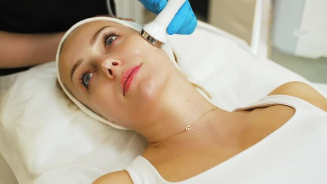 SPA treatment day. Closeup indoor portrait of lying attractive caucasian woman during microdermabrasion procedure performed by professional unrecognizable cosmetician. High quality 4k footage