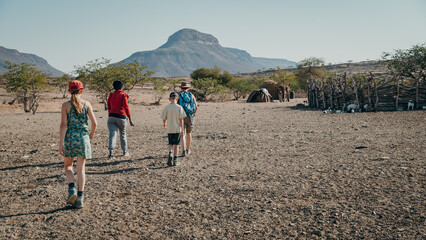 Touristen gehen durch ein Himba-Dorf, Kaokoveld, Namibia