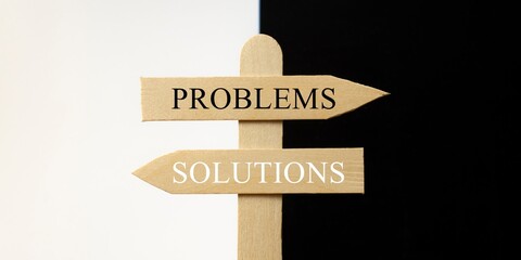 Cartel de madera señalando problemas hacia el lado negro y soluciones hacia el blanco	