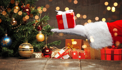 Obraz premium Santa Claus hand holding a wrapped Christmas present.