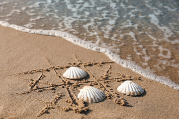 Playing Tic tac toe game with shells on sand near sea