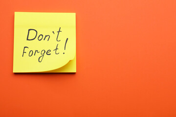 Paper note with phrase Don t Forget on orange background, top view. Space for text