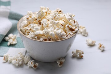 Bowl of tasty popcorn on white table, closeup