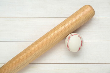 Baseball bat and ball on white wooden table, top view. Sports equipment