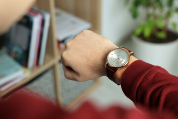 Man checking time in room, closeup. Being late
