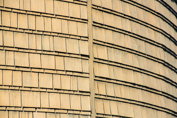 Row of rugged wooden tiles on side of building with round facade on the side of building or structure with yellow color on side