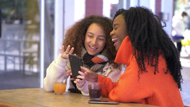youth, technology - friends chat and laugh while looking at photos on phone
