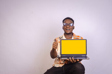 Excited young black male holding laptop giving thumbs up