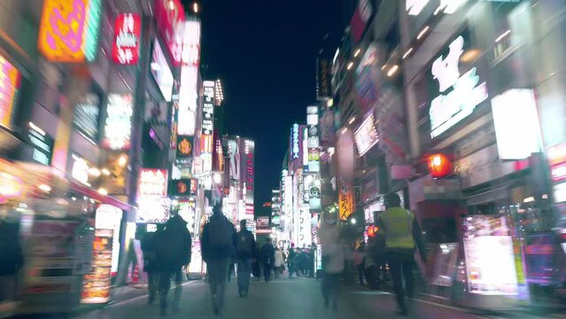 Tokyo, Japan - December 9, 2022: hyper lapse video of urban nightlife in Asian metropolis, crowd of people walking along illuminated streets of entertainment district Kabukicho in Tokyo