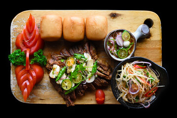 Grilled thai beef served with papaya salad, vietnamese buns and kumquat sauce top view