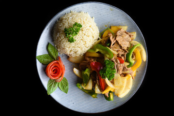 Stewed beef with vegetables with rice on blue plate isolated on black background top view 